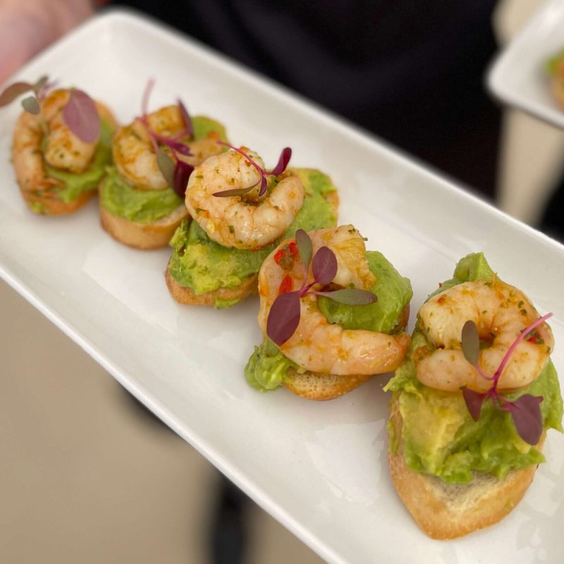 Person holding a platter of prawns